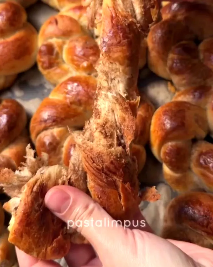 Golden pull-apart açma rolls with poppy seed swirls on a parchment-lined baking sheet