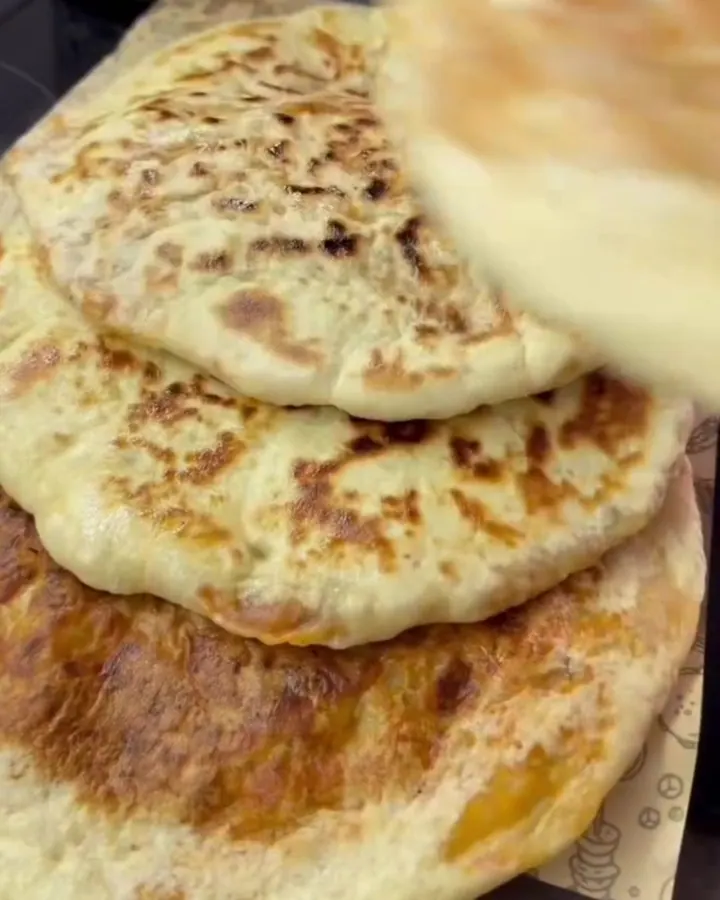 Torn open potato bazlama flatbread with steam rising and buttery crust