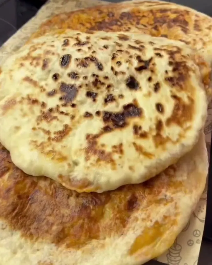 Buttery potato-stuffed flatbread torn open showing steam and layered dough