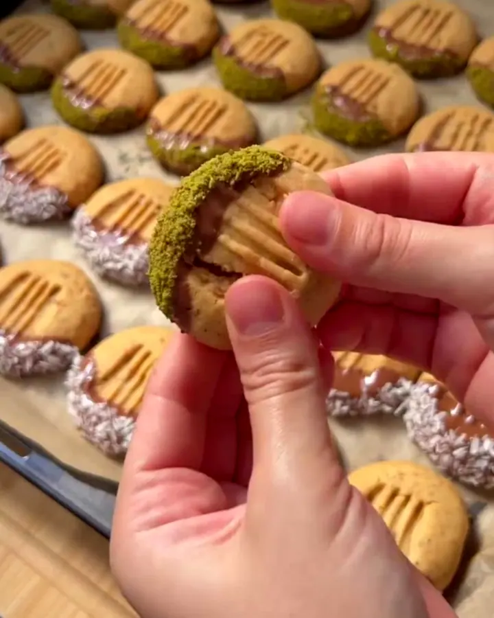 Chocolate-dipped walnut shortbread cookies stacked on a parchment-lined tray, showing a glossy chocolate coating.