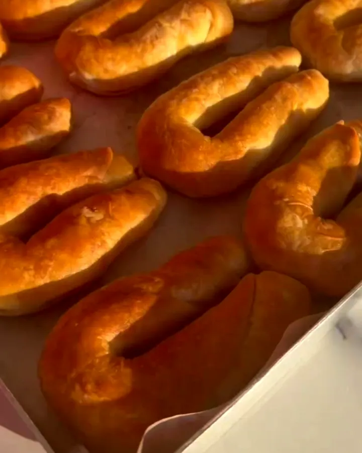 Golden blistered börek rolls on a parchment-lined baking sheet, one snapped in half showing flaky layers and beef filling.