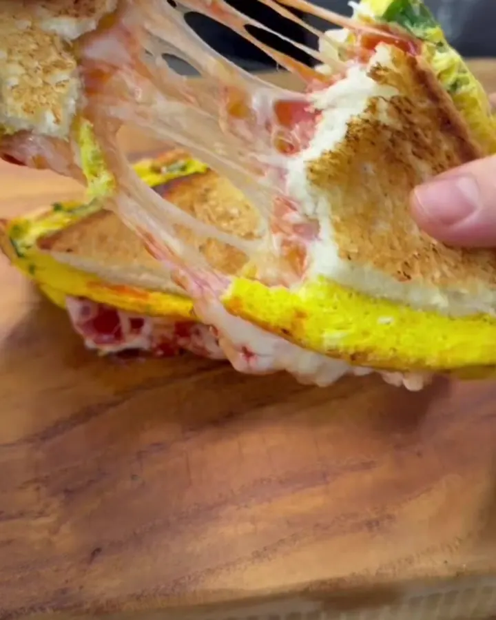 Golden brown pull-apart egg toast sandwich with molten cheese stretching between the halves.