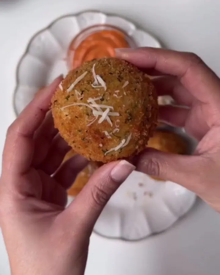 Golden crispy potato balls dusted with Parmesan, one broken open showing stretchy mozzarella