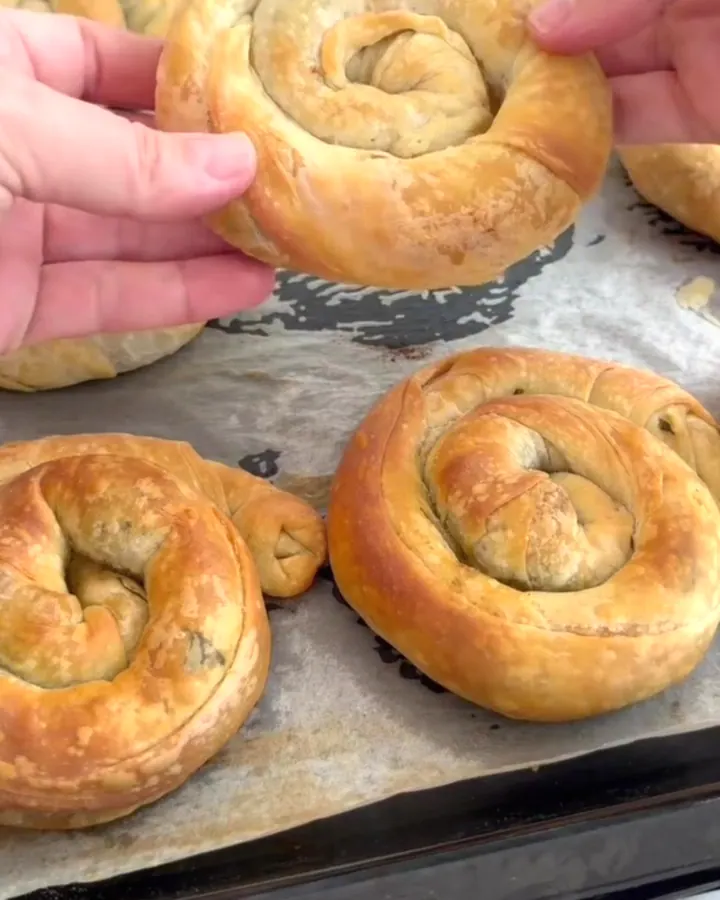 Golden spiral rose börek with spinach and cheese filling, broken apart to show steaming interior