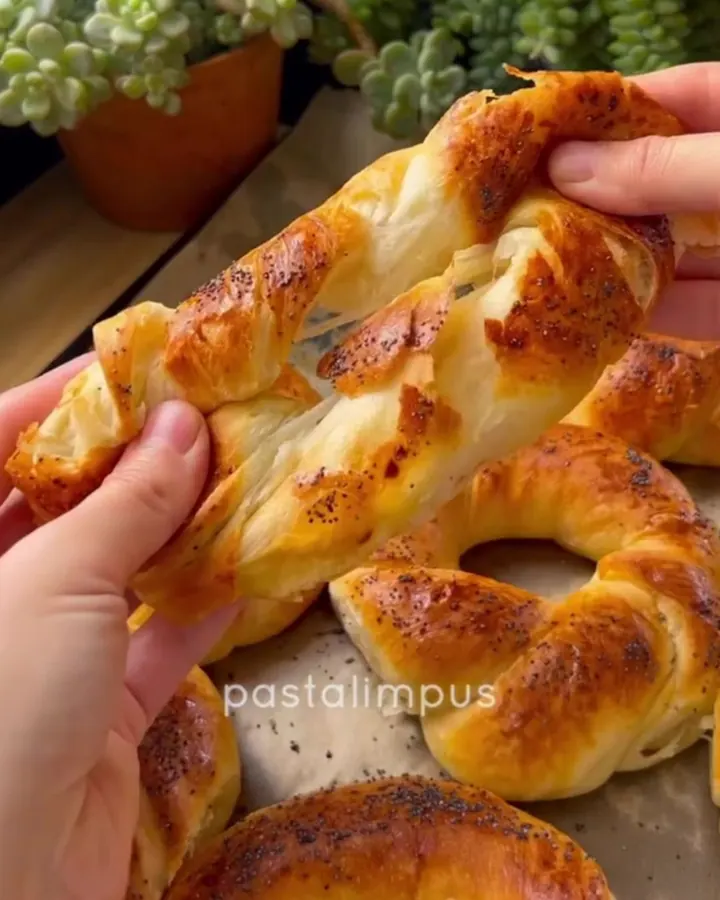 Warm Turkish açma bread pulled apart, showing soft buttery layers and sesame seed crust