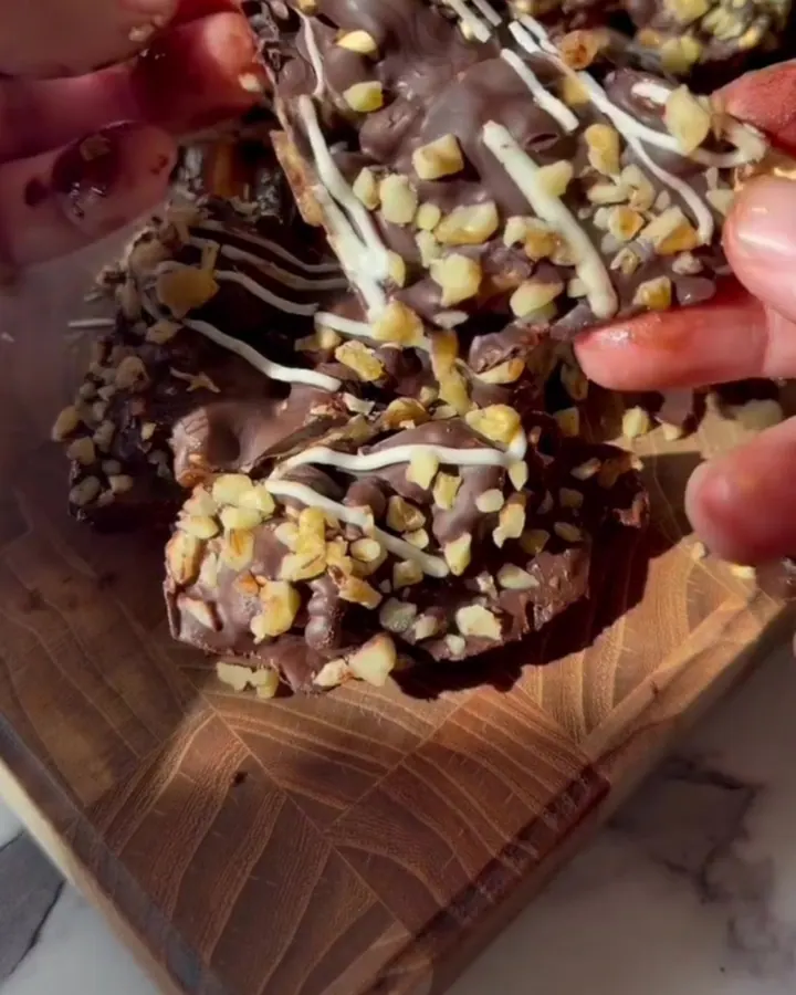 Frozen date bark sliced into bars, showing layers of dates, peanut butter, and chocolate with nut topping.