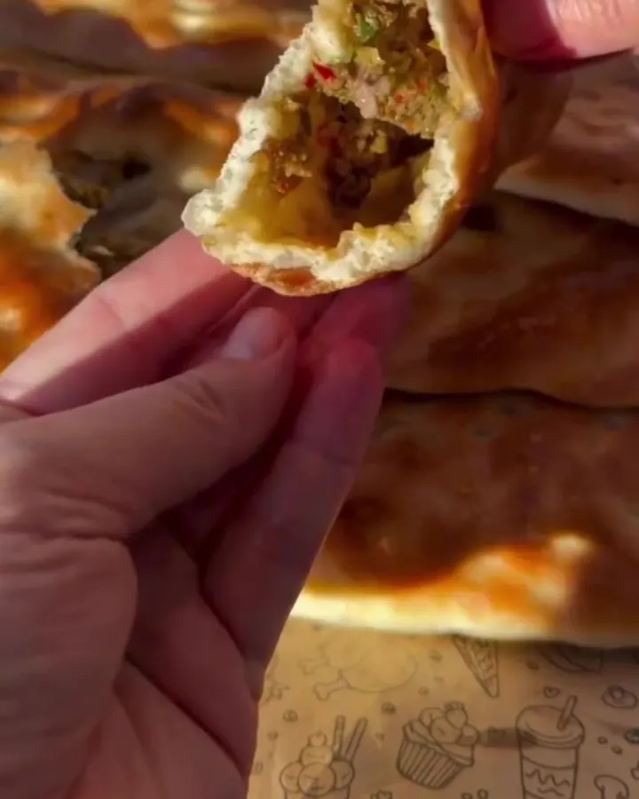 Golden stuffed pide torn open, showing juicy spiced ground beef filling and steam rising.