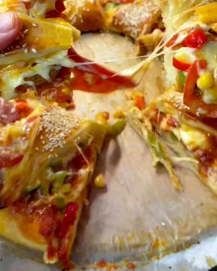 Golden ring pizza with melted cheese and toppings on a parchment-lined baking sheet