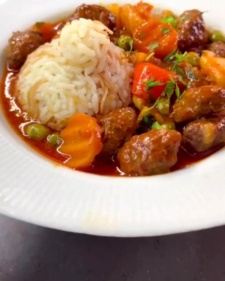 Ladle of hearty meatball stew with potatoes and chickpeas in a rustic ceramic bowl