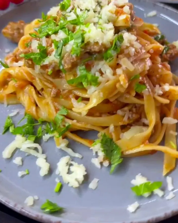 Twirled tagliatelle with beef ragù and melted mozzarella in a skillet