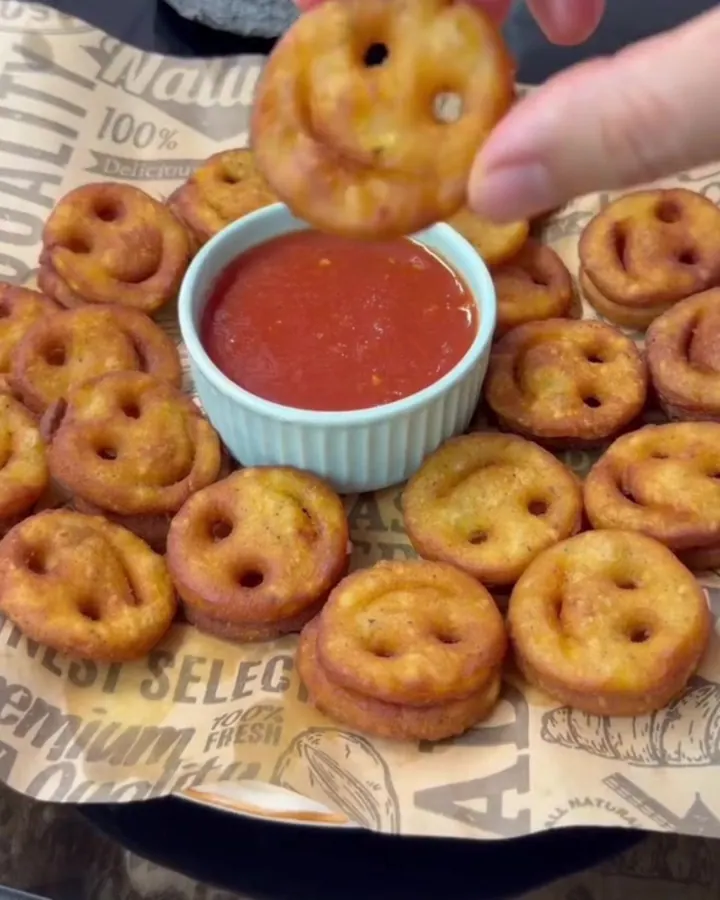 Golden crispy bread chips with smiling faces piled in a strainer