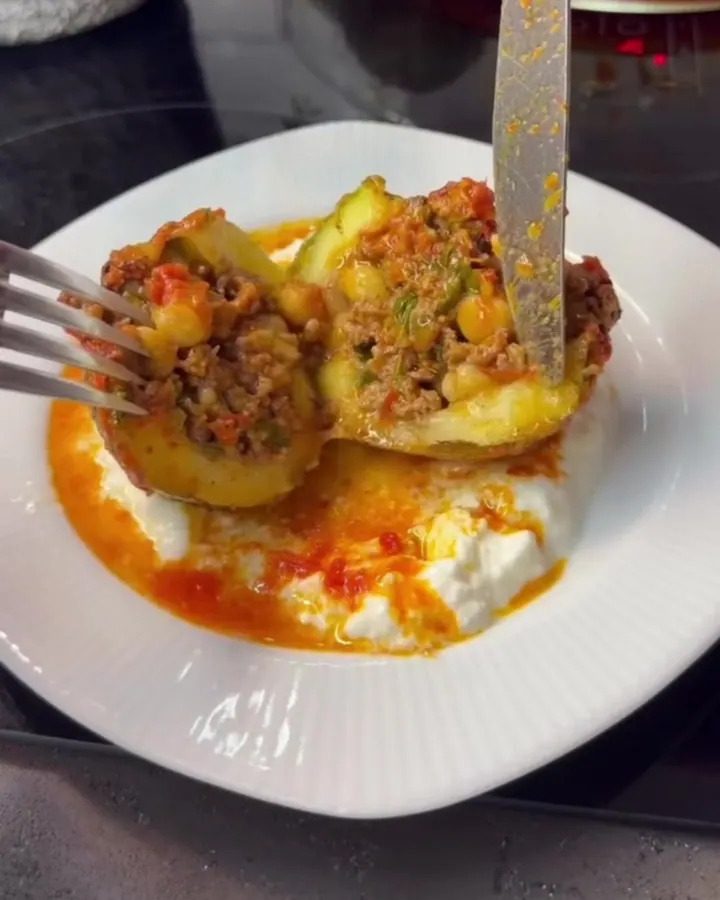 Baked stuffed round zucchini cut in half, showing rice, chickpeas, and ground beef in tomato broth