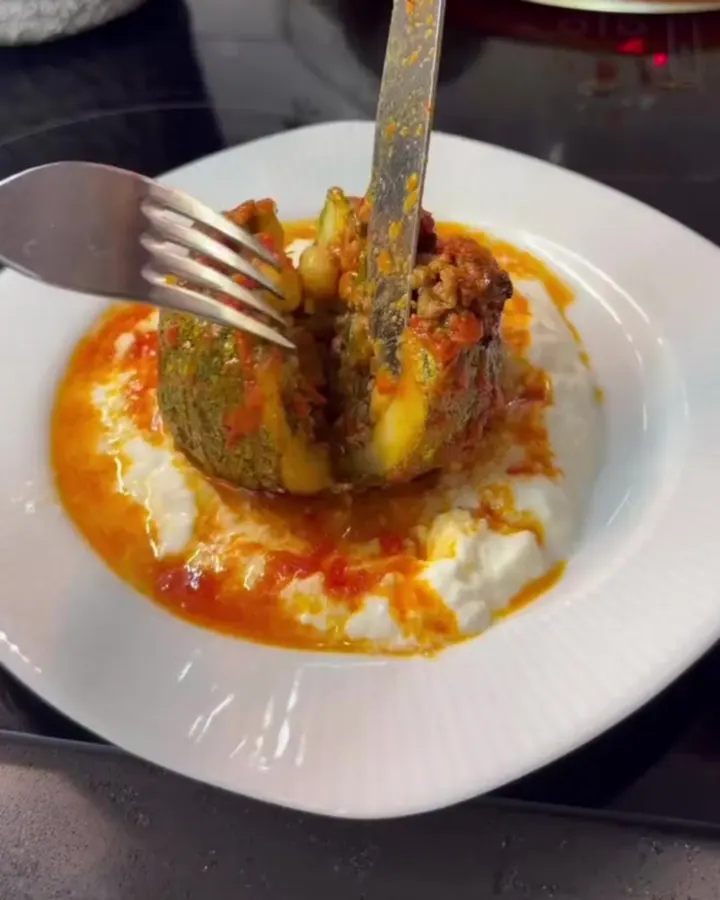 Stuffed round zucchini with spiced beef and chickpeas, braised in tomato broth, on a deep plate