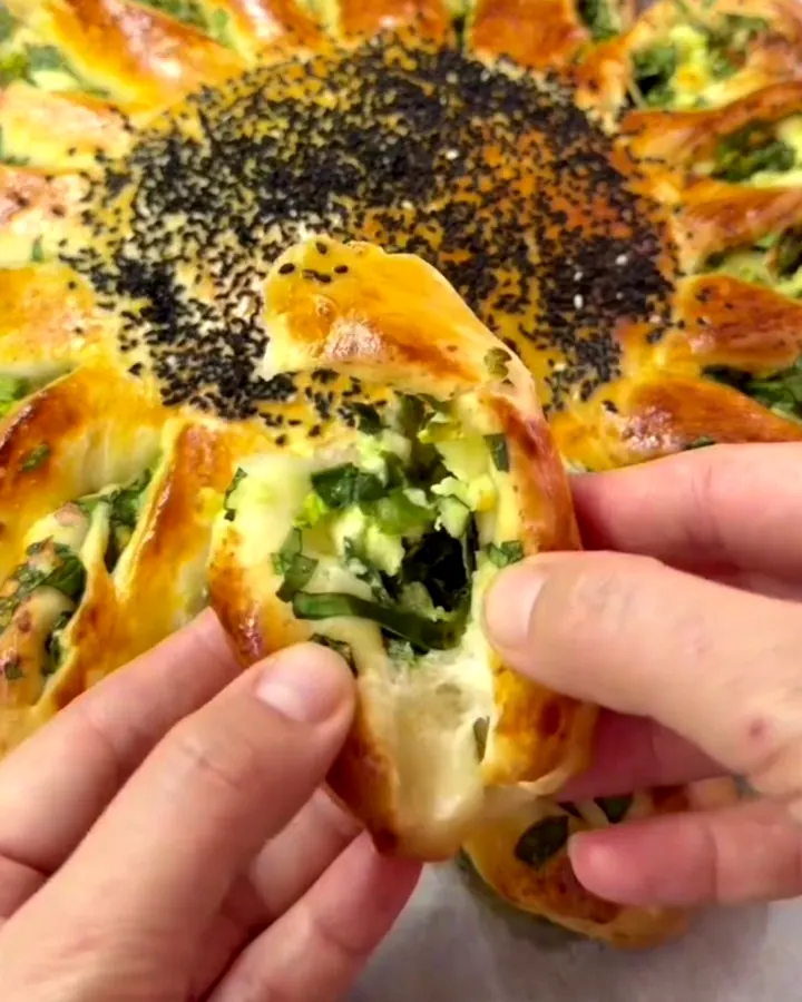 Golden pull-apart sunflower bread with spinach and feta filling on a baking sheet.